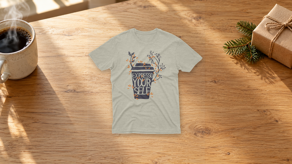Sand Expresso Yourself coffee graphic tee on a warm wood table beside coffee and a wrapped gift.