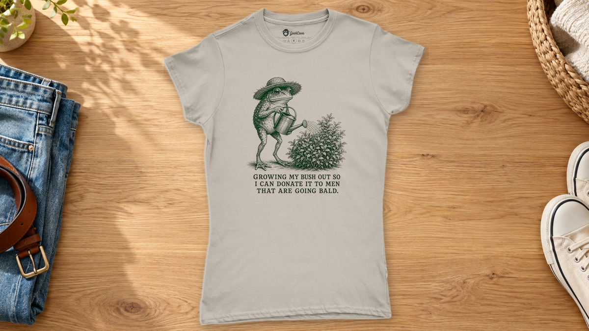 Sand funny frog graphic tee styled beside folded jeans, a belt, and white sneakers on a wooden surface.