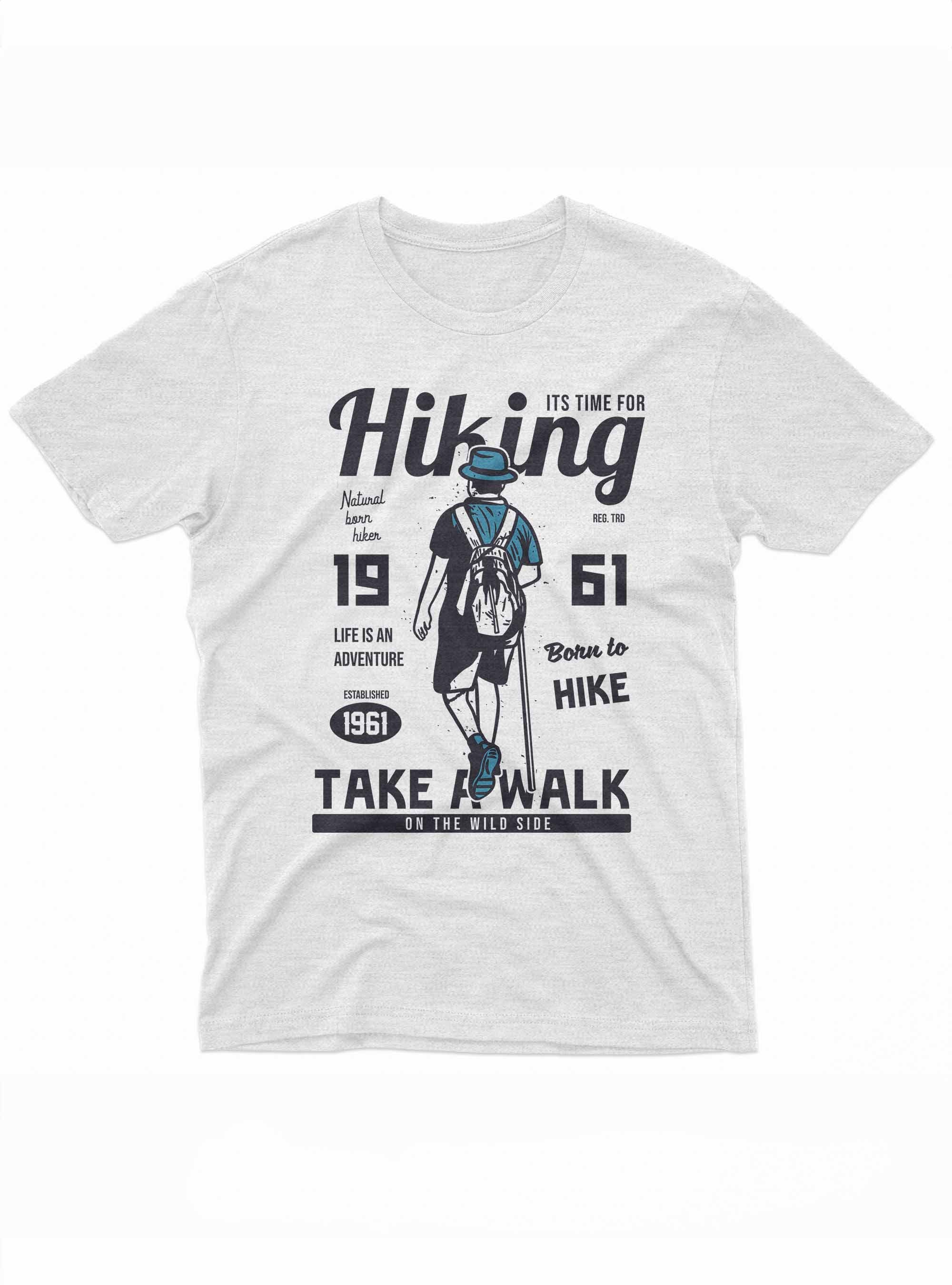 The image depicts a dark t-shirt with a design centered around the theme of hiking. It features the silhouette of a hiker in blue, viewed from the back, wearing a hat and a backpack. Large text above and below the figure reads 