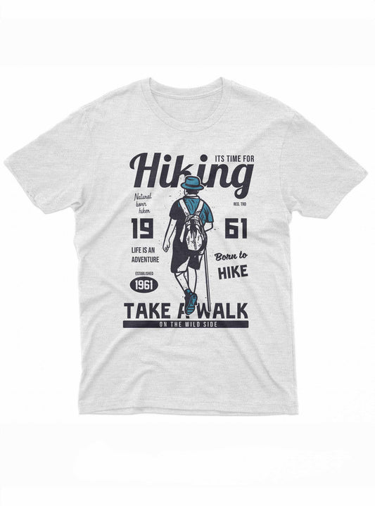 The image depicts a dark t-shirt with a design centered around the theme of hiking. It features the silhouette of a hiker in blue, viewed from the back, wearing a hat and a backpack. Large text above and below the figure reads "Hiking" and "Take a Walk on the Wild Side"