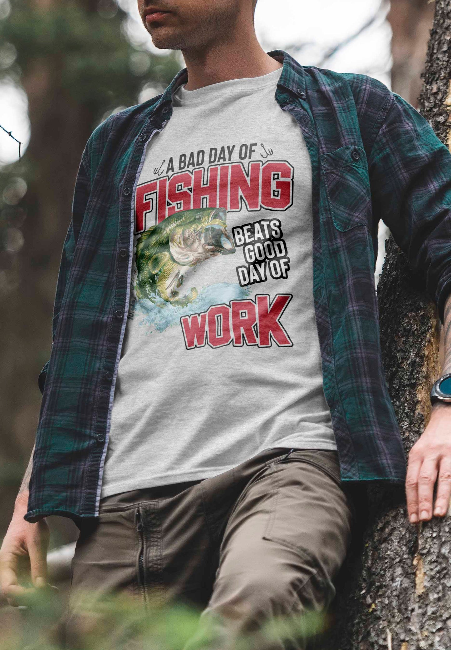 the image features a t-shirt design with the phrase "fishing beats good day of work" in bold red letters at the top and bottom. the central graphic is a colorful, detailed illustration of a large green bass leaping out of blue water, capturing the energy and excitement of fishing.