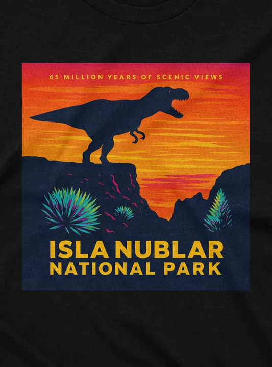 Black T-shirt featuring a colorful vintage-style graphic of a T-Rex silhouette standing on a cliff at sunset, with text that reads "Isla Nublar National Park – 65 Million Years of Scenic Views", resembling a retro national park poster.