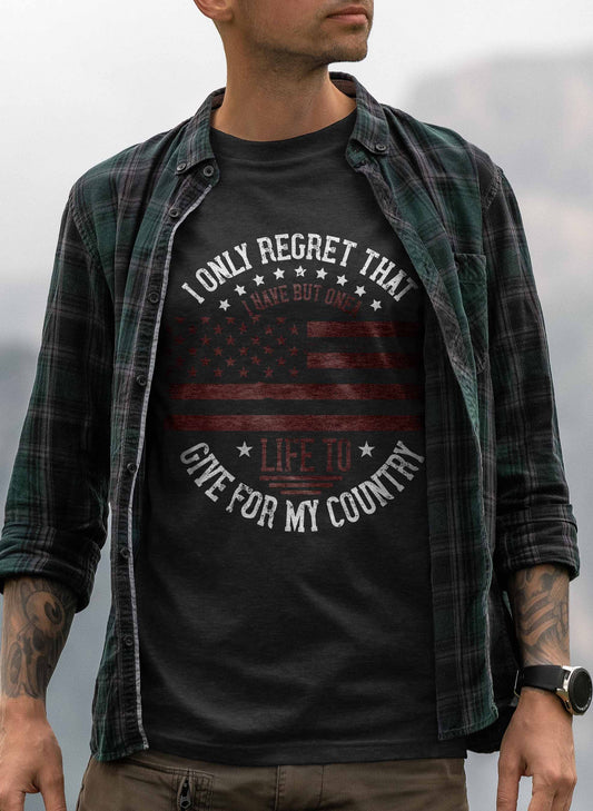 A t-shirt design showcasing a distressed American flag, with stars on the upper half and stripes on the lower half, all in muted tones. The phrase "I Only Regret That I Have But One Life to Give for My Country" curves around the top and bottom of the flag, symbolizing deep national pride and sacrifice.